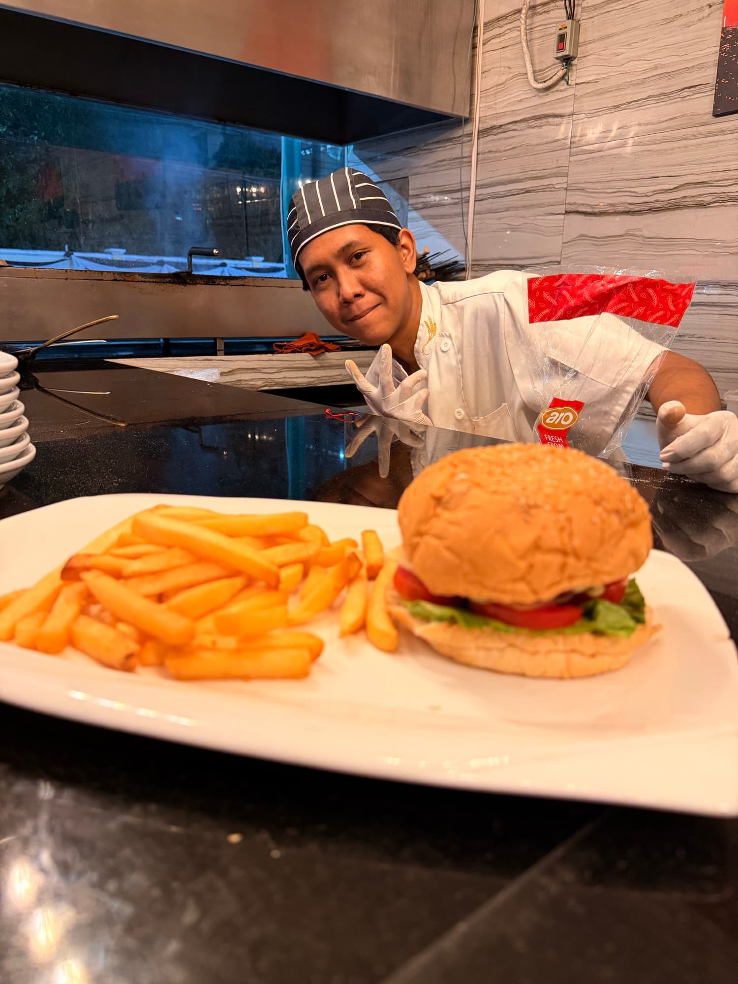A Mr. TUNA chef at the pass with a burger and fries