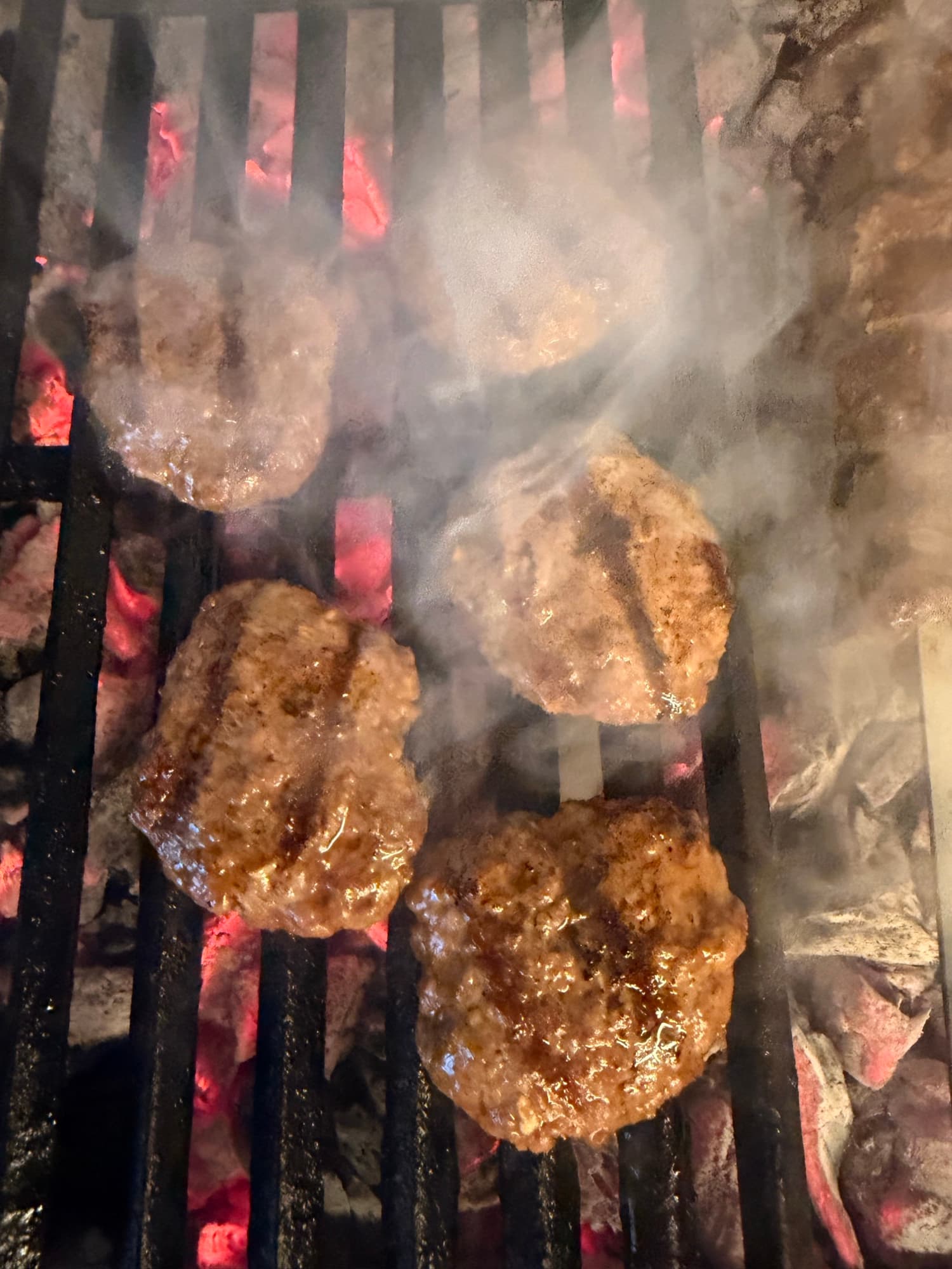 Köfte cooking over charcoal as the smoke rises off the grill