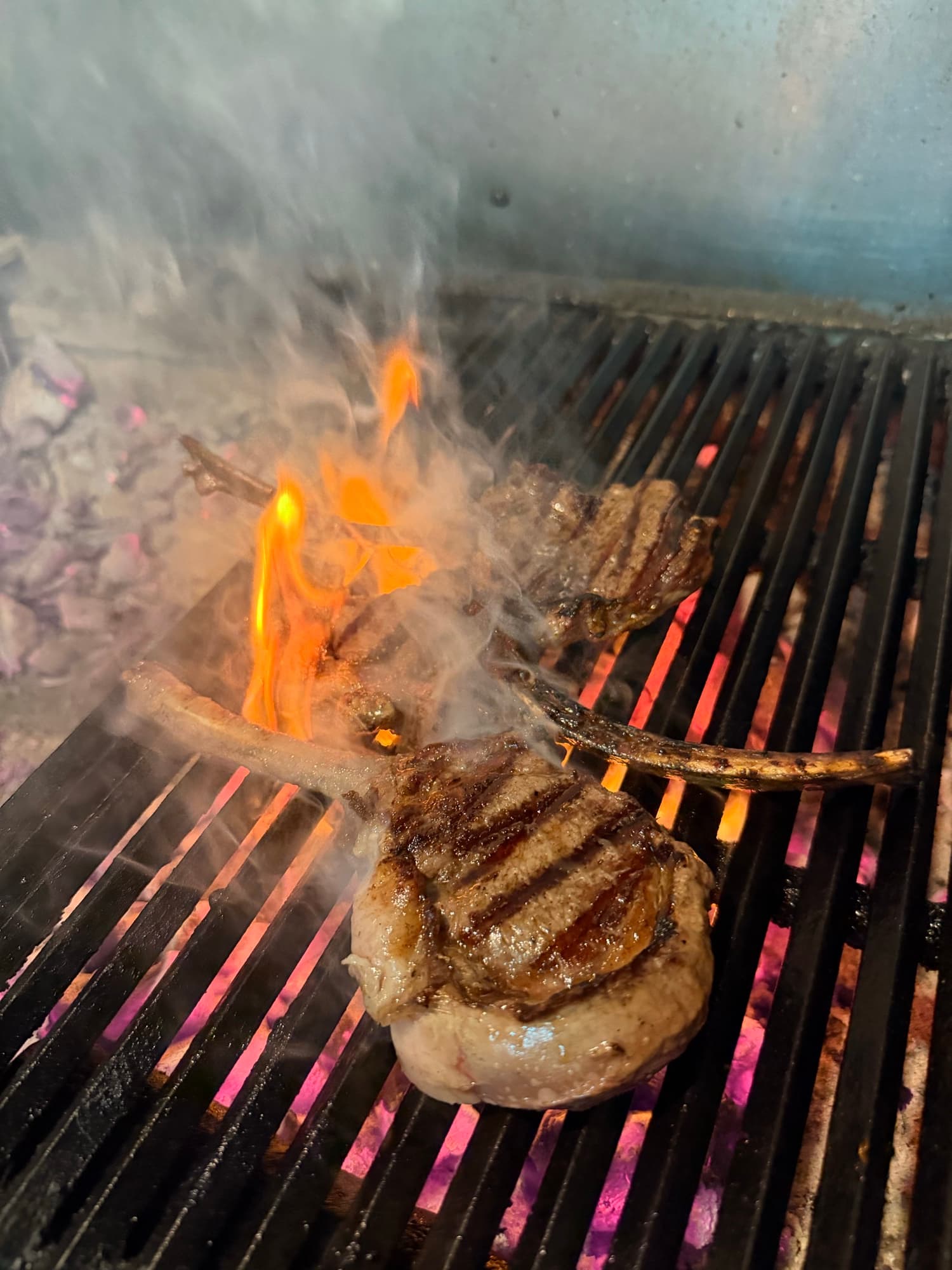Lamb chops and a thick-cut steak over the charcoal flames