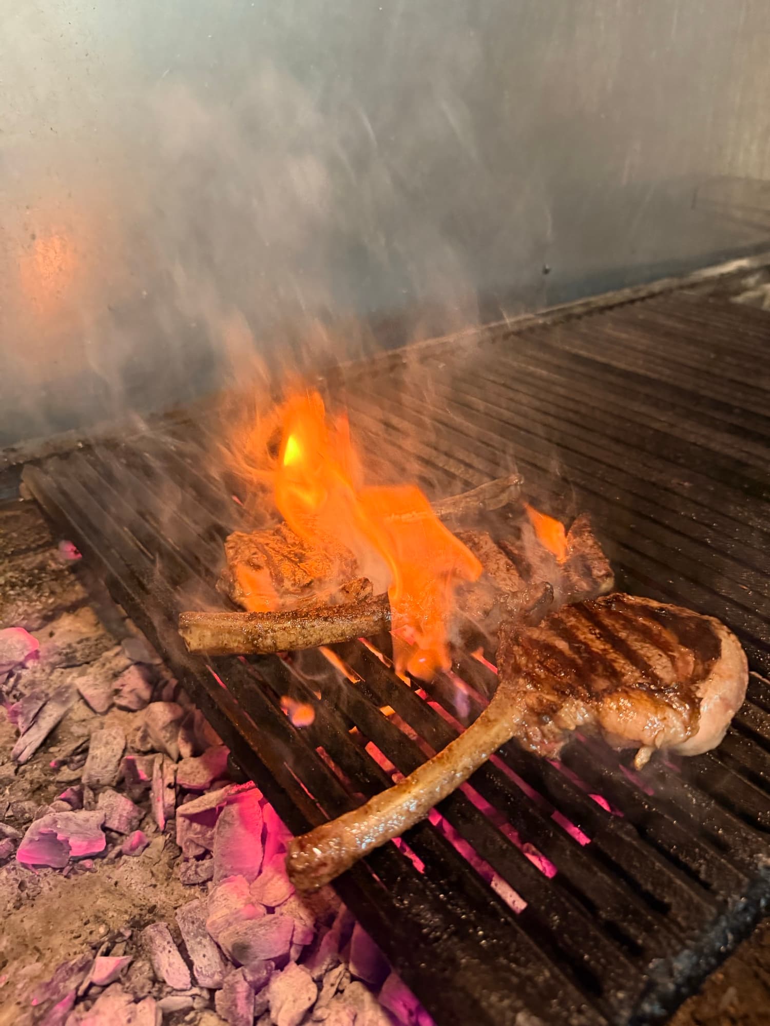 Tomahawk steak resting at the edge of the charcoal grill