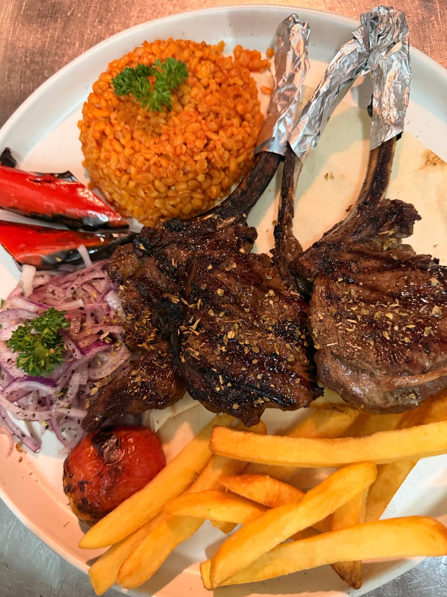 Lamb chops with bulgur pilaf, fries and a charred tomato