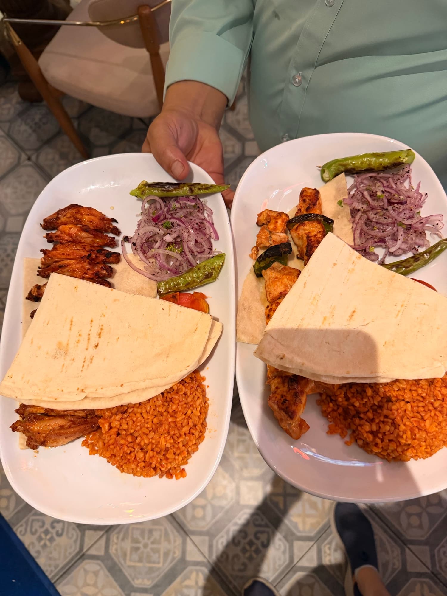 Two grill plates with lavash, bulgur pilaf and pickled red onion