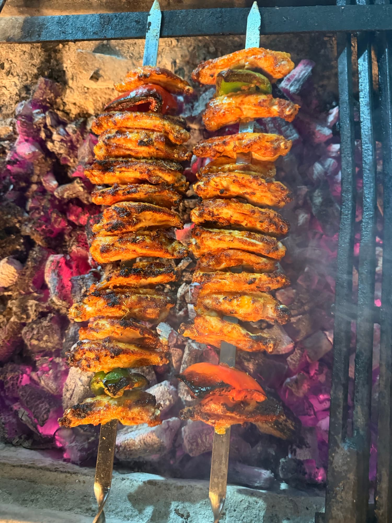 Chicken and vegetable skewers over glowing charcoal